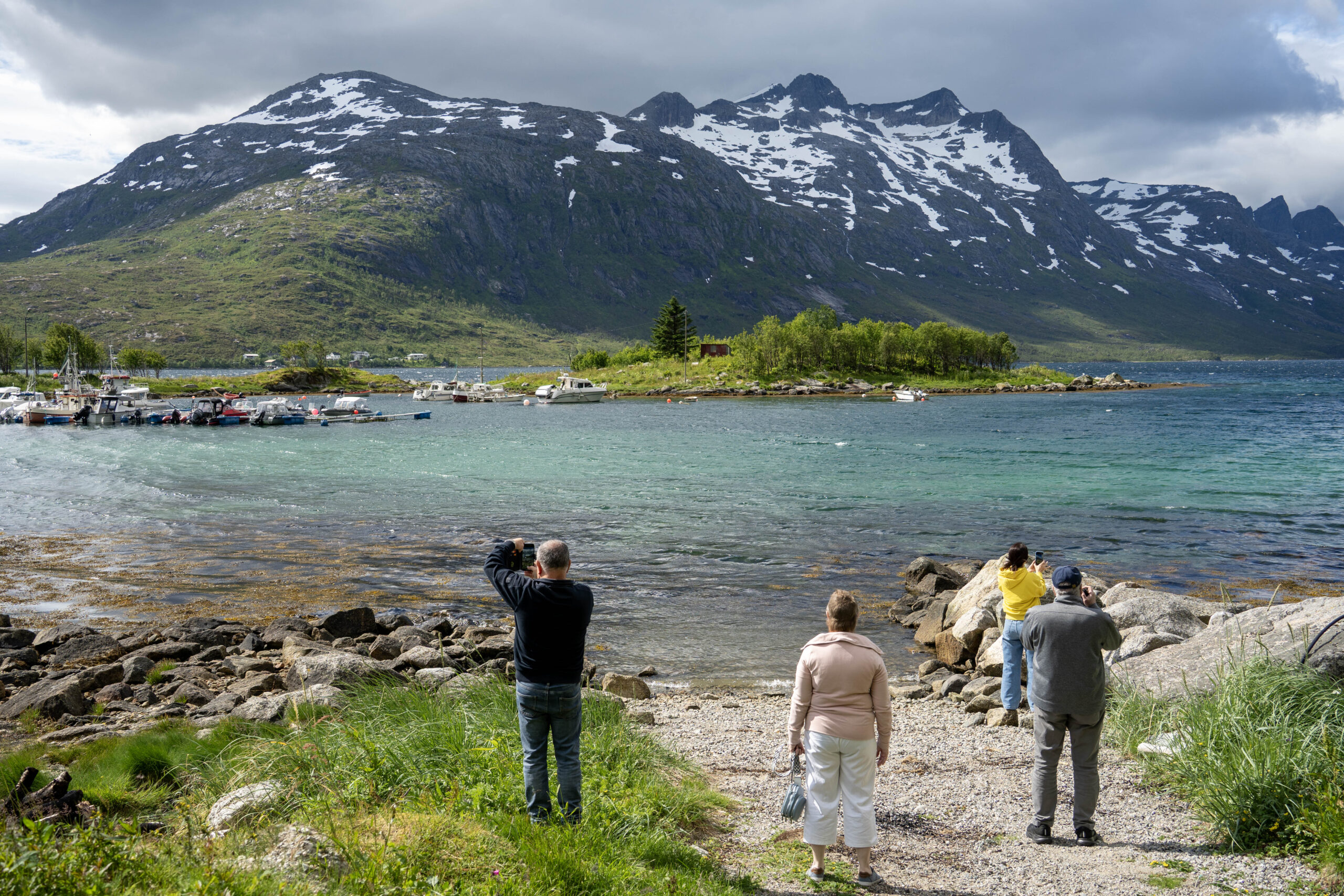 A groups of people walking down to the water front of a fjord